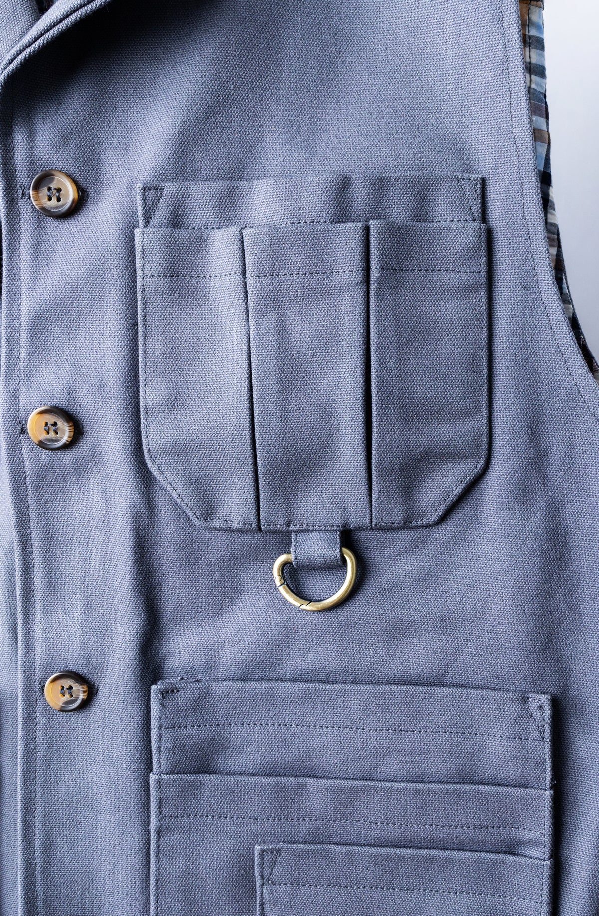 Grey tool vest chest pocket with brass D-ring and button closure