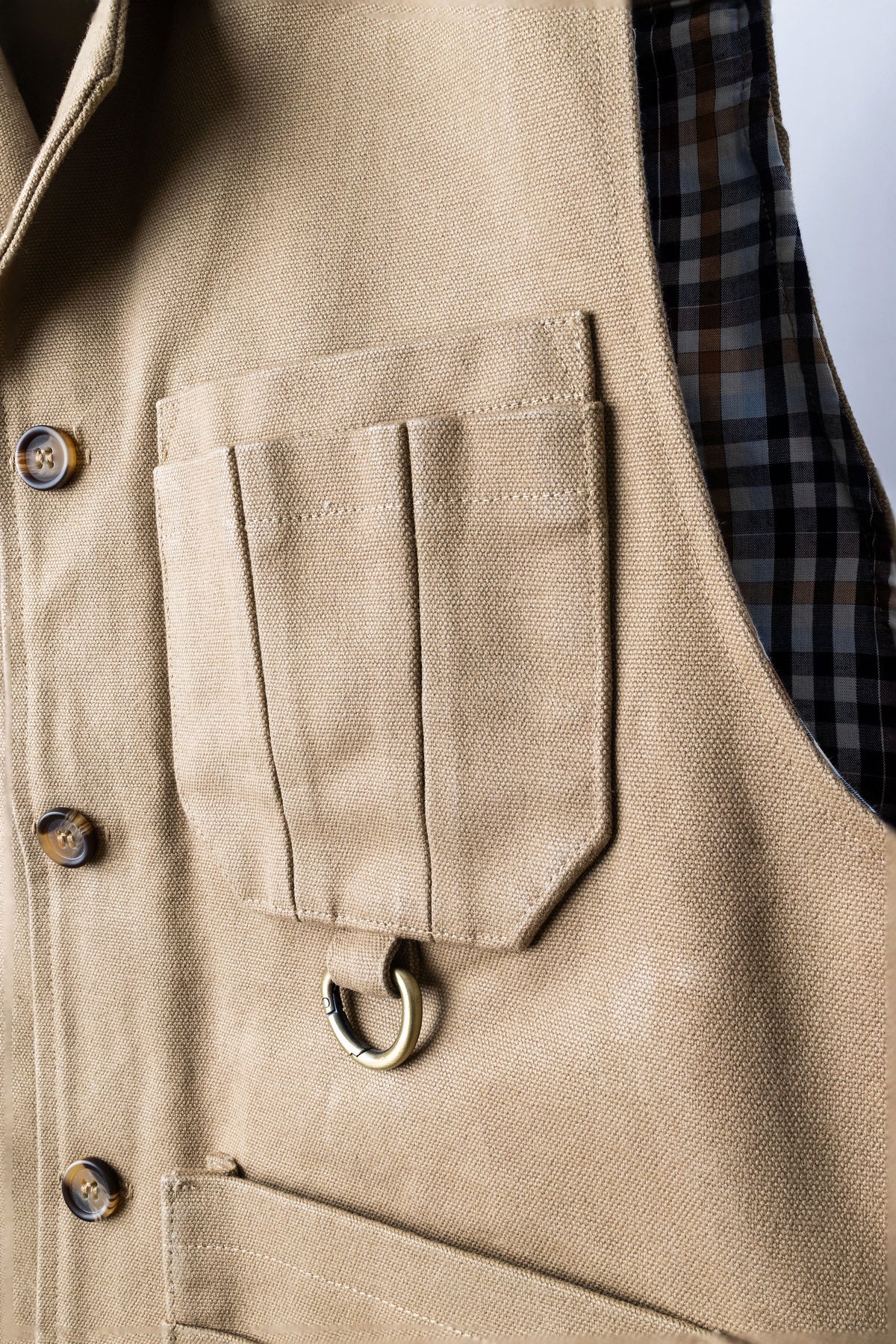 Close-up of khaki Iron Tradesman vest front pockets and button closure. Duck Canvas USA Made