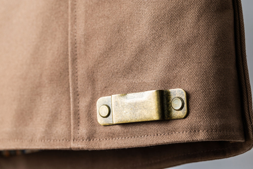 Duck canvas tool vest. Close up of a tape measure clip or drill clip.